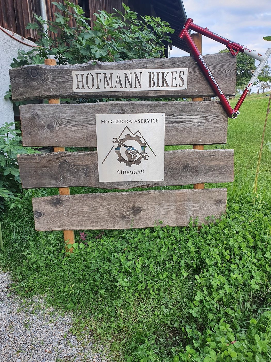 Hofmann Bikes: Werkstattschild und Fahrradrahmen im Grünen